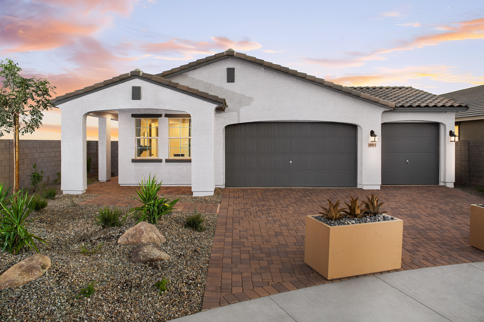 paver driveway with planters and a covered entry