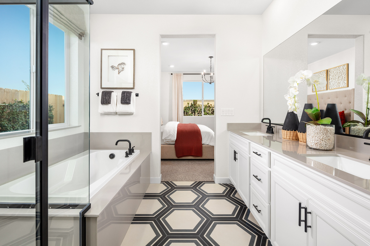 bathroom with white cabinets, two sinks, and tub