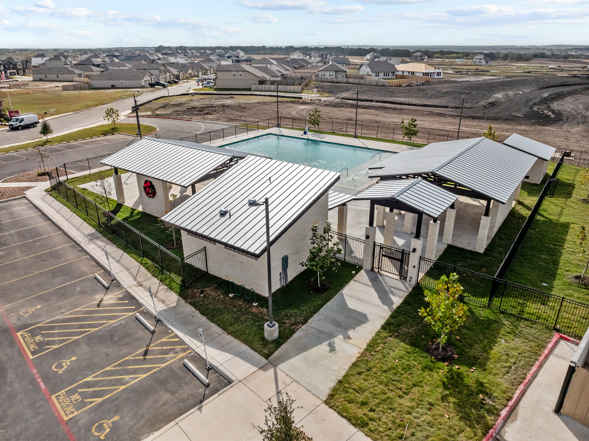 pool & amenity center with a black gate & grass