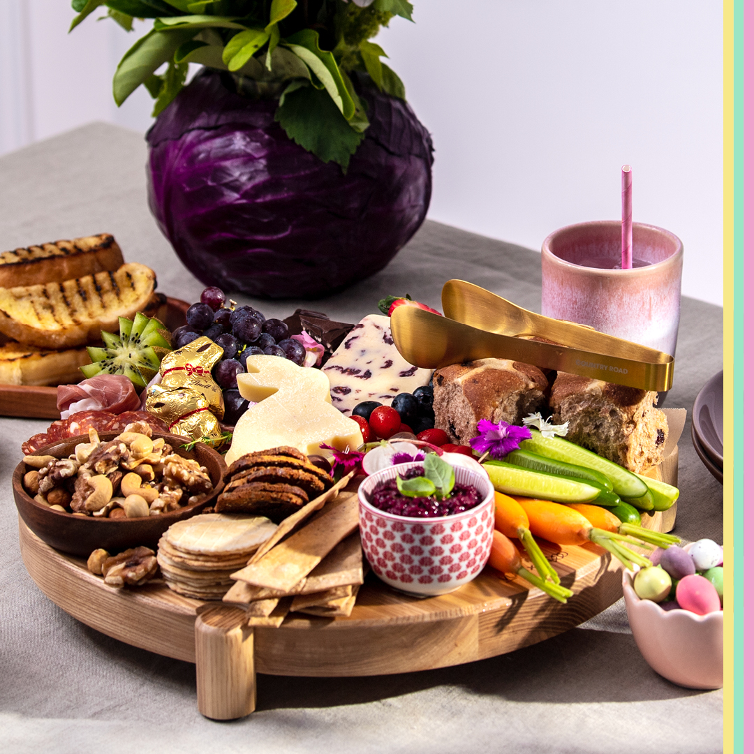 Easter inspired grazing platter featuring cheese, crackers, hot cross buns, carrots, cucumber, bread olives and more