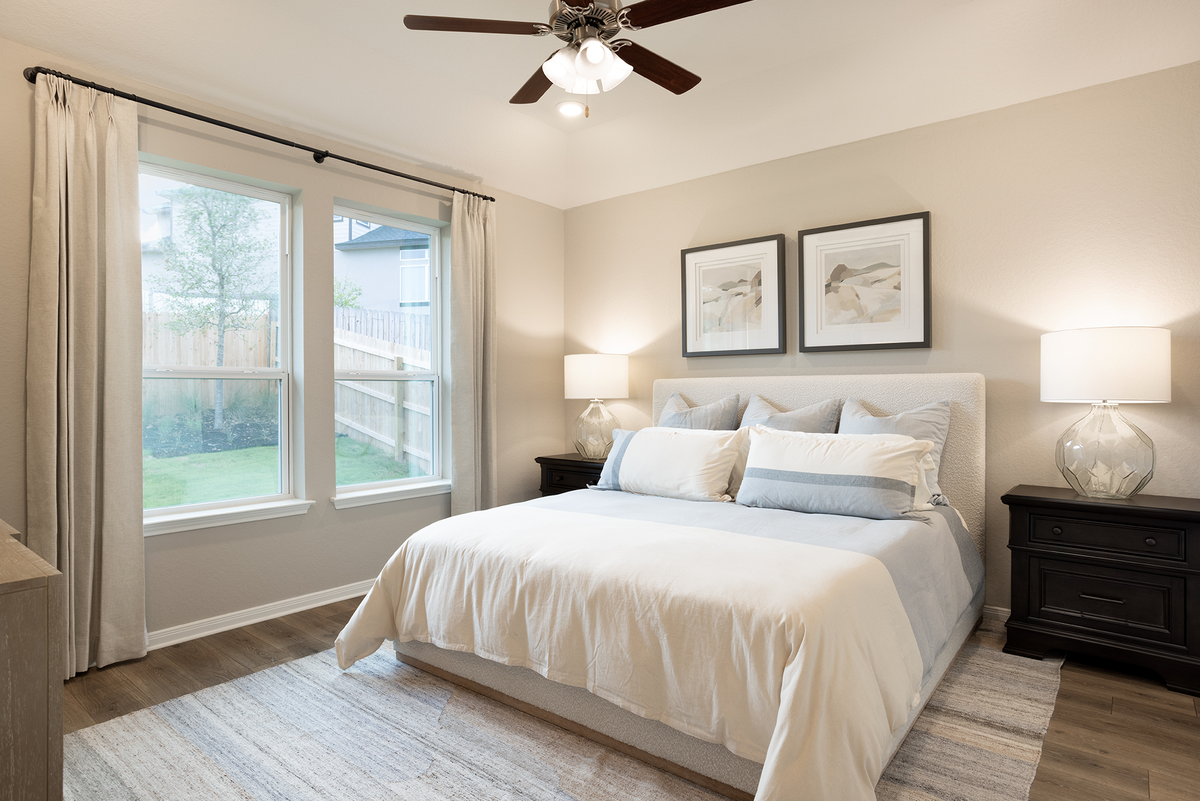 primary bedroom with brown flooring & windows