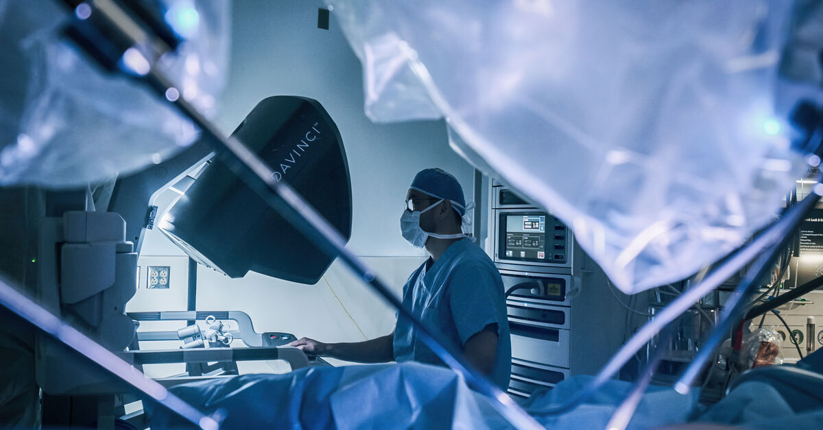 surgeon in OR next to DaVinci machine