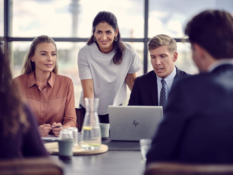 Mehrere Personen sitzen an einem Tisch, um einen Laptop