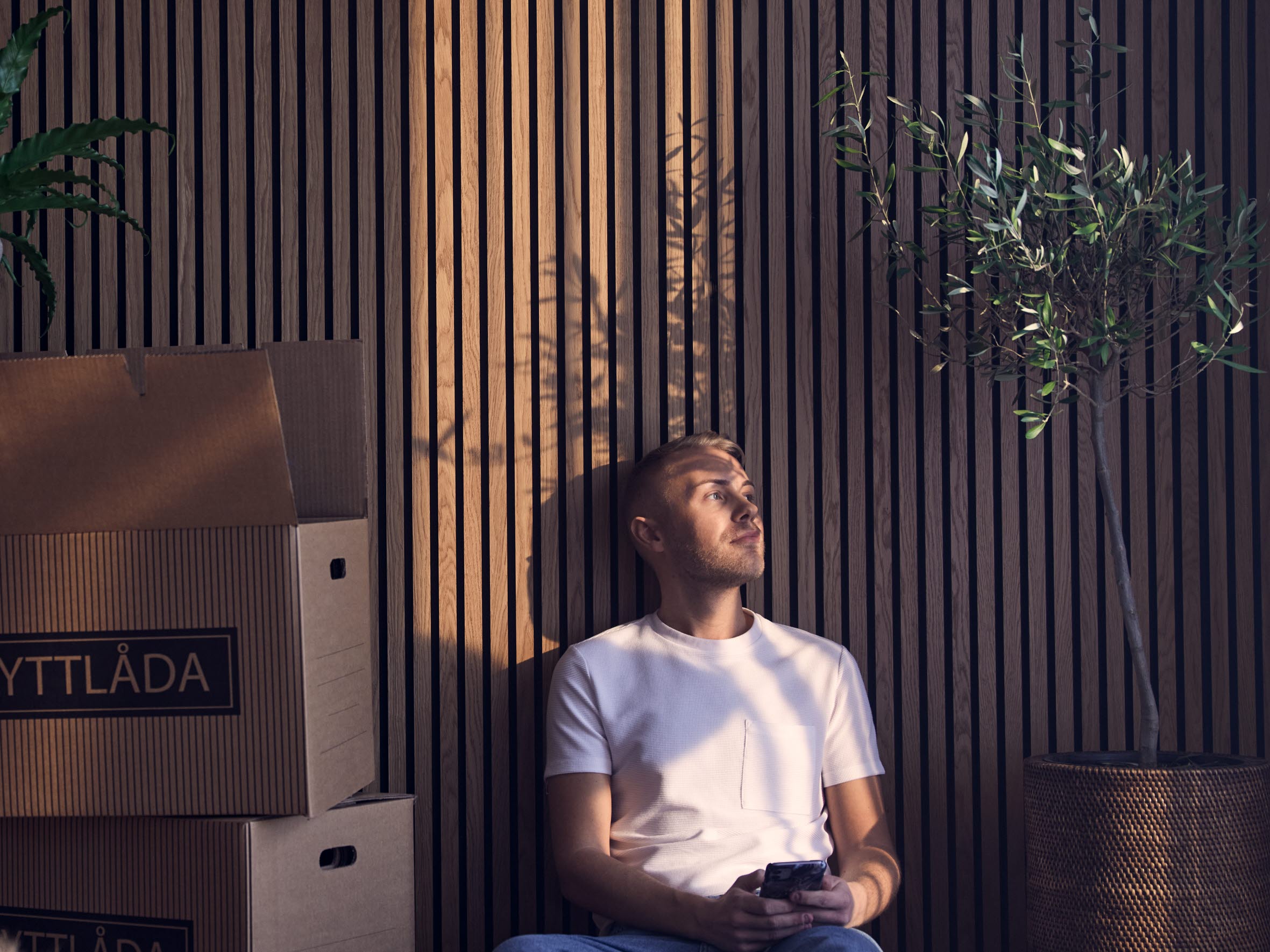 Ung man sitter på golvet bland flyttkartonger.