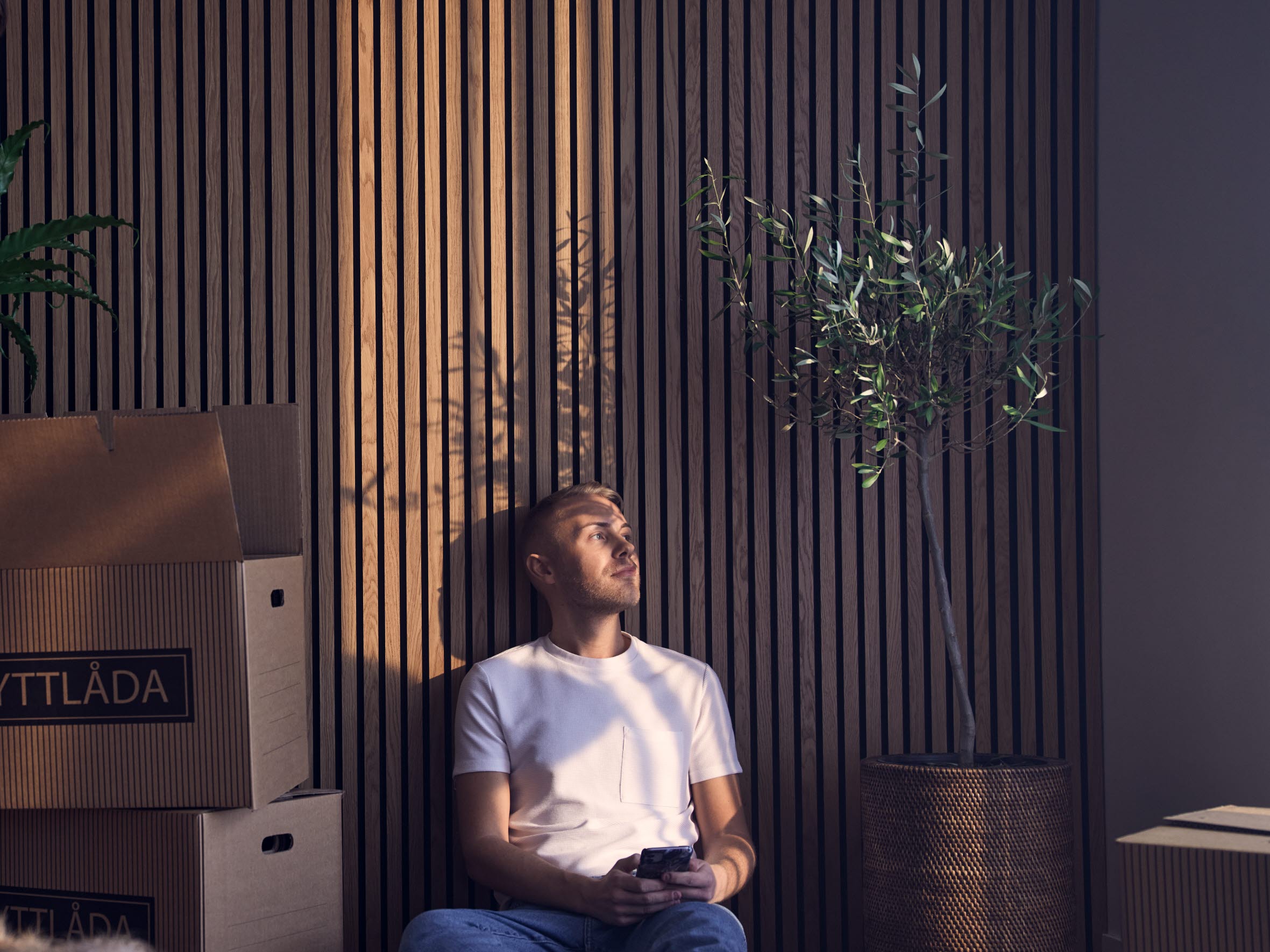 Ung man sitter i ett tomt rum med flyttlådor.