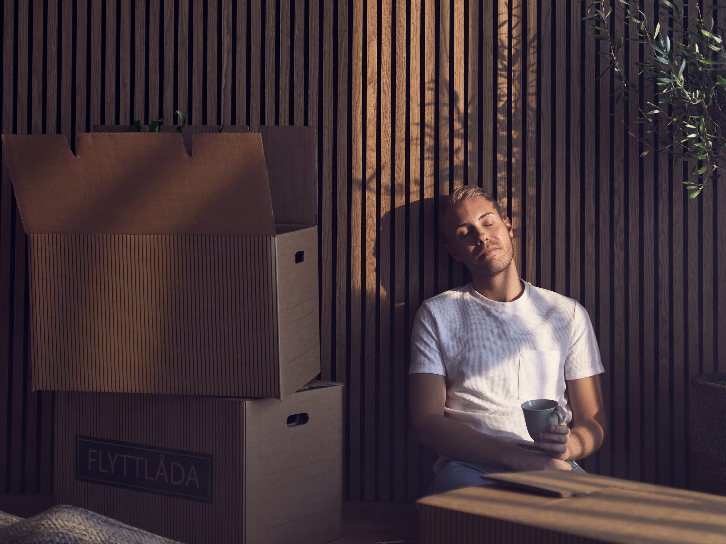 Man sitter på golvet bredvid flyttlådor.