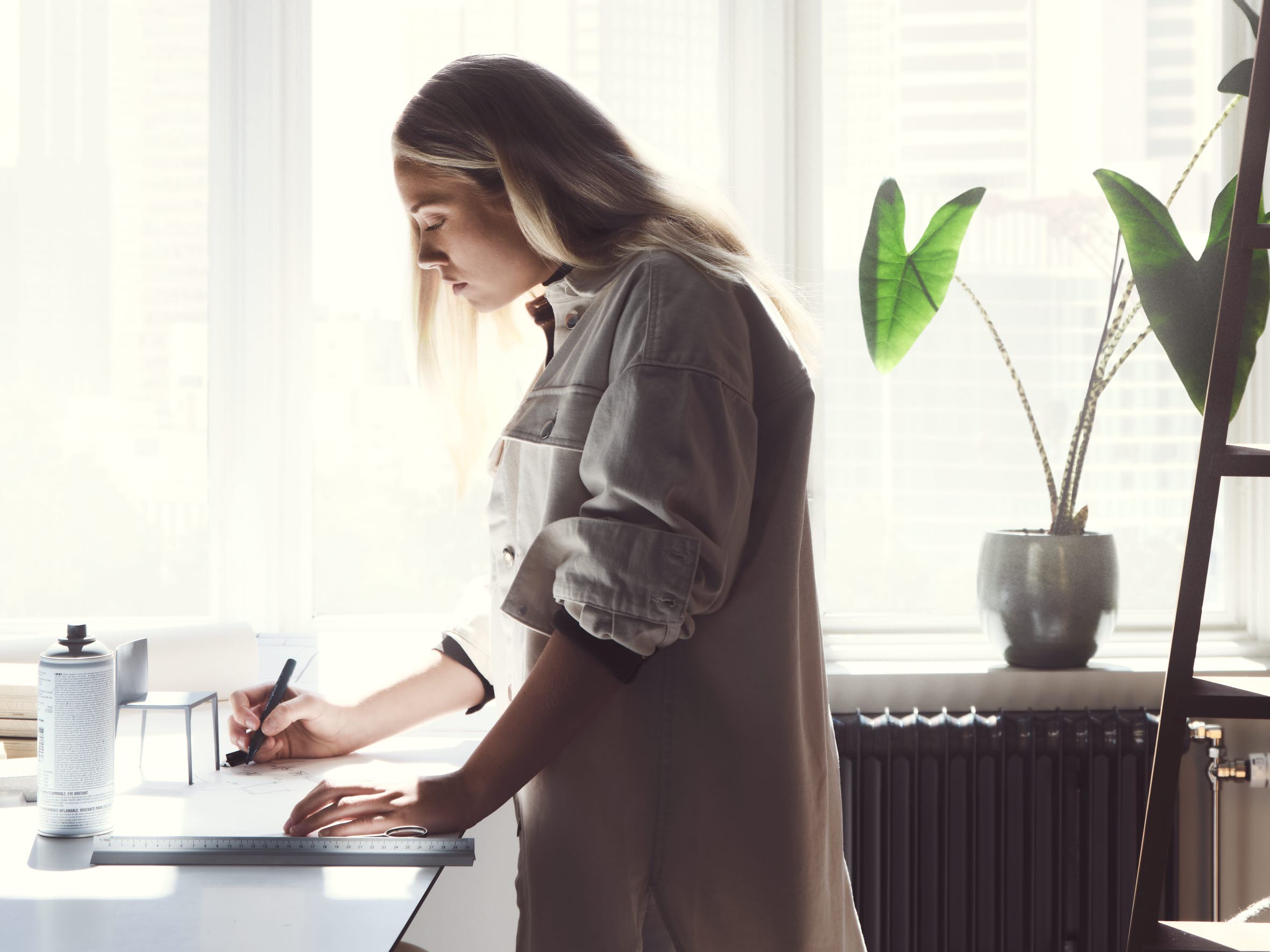 Kvinna står vid ett skrivbord framför ett fönster