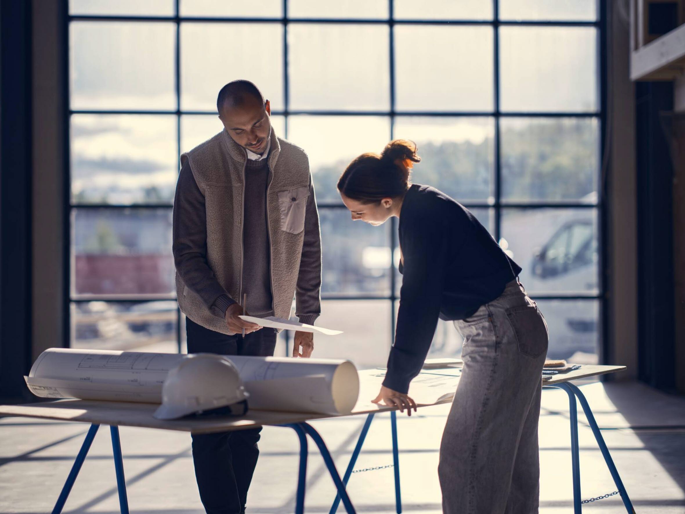 Man och kvinna står lutade över ett bord med ritningar.