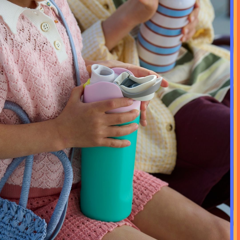 2 children sitting on a bench seat holding water bottles