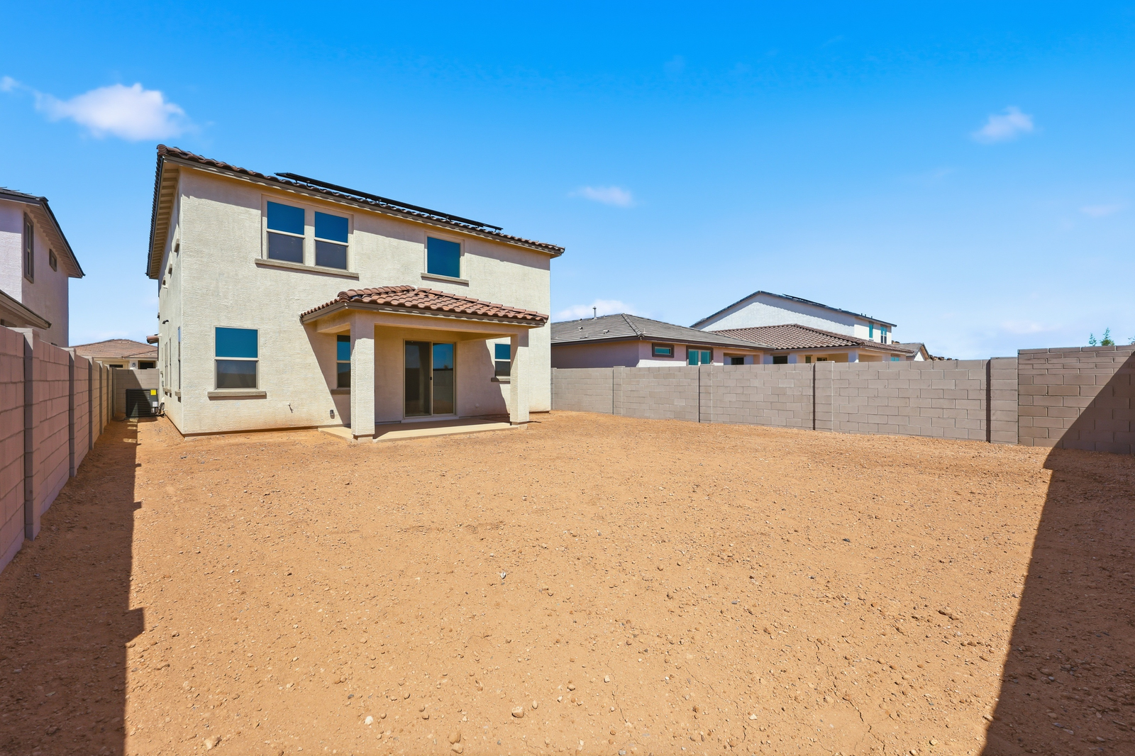 spacious dirt backyard with a concrete block wall