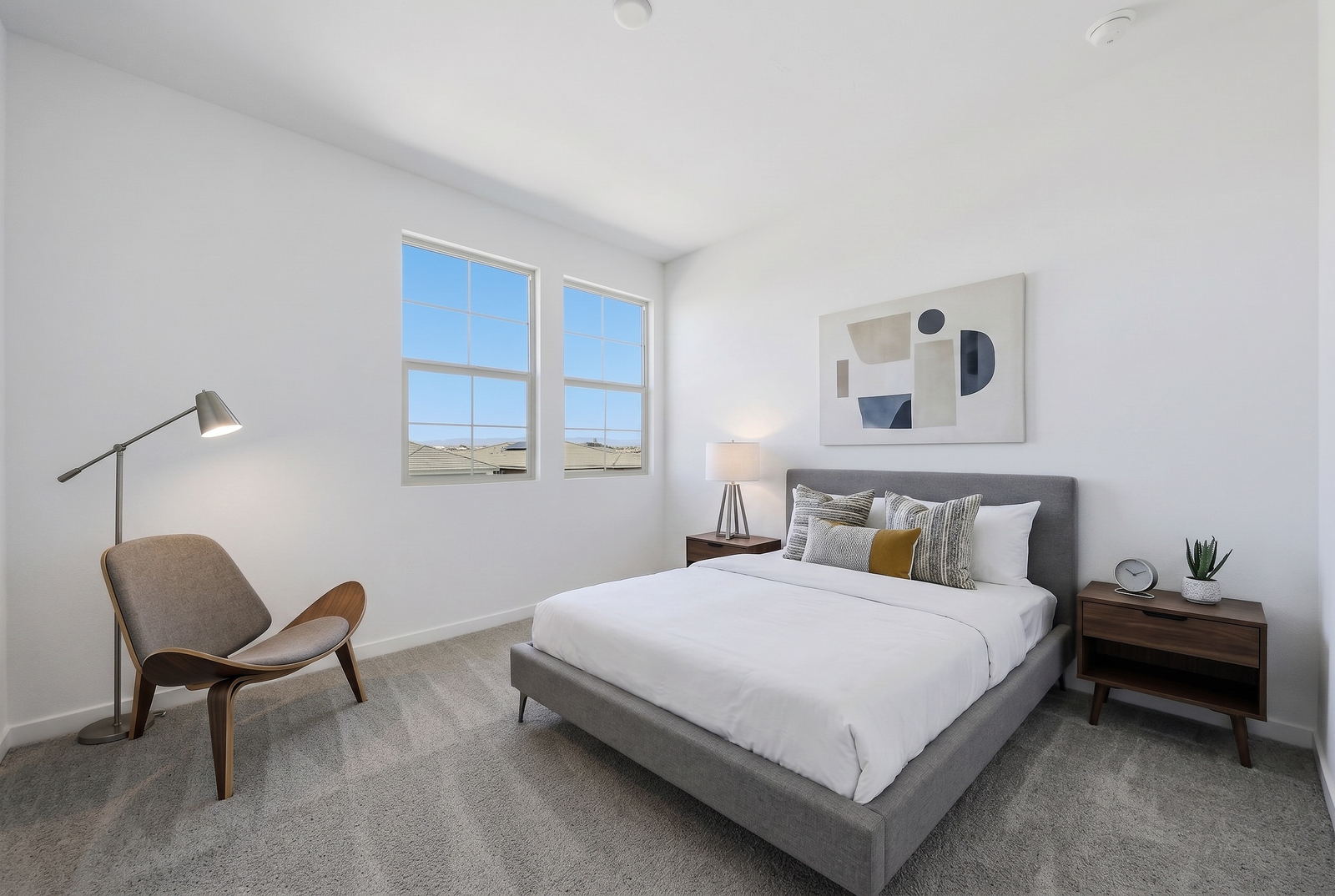 bedroom with a large bed, a grey bedframe, and walnut nightstands
