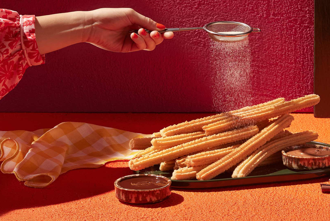 Dusting churros with cinnamon sugar