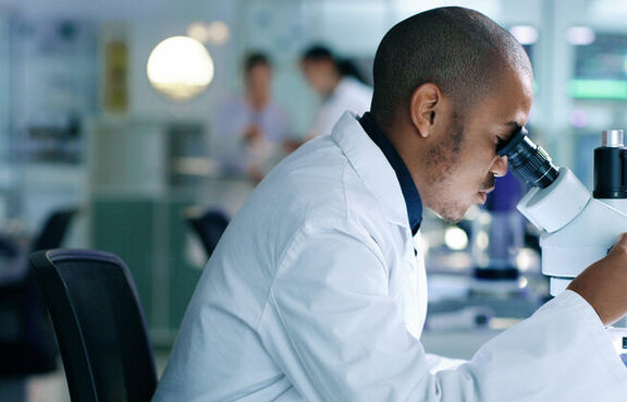 Scientist looking at sample through a microscope