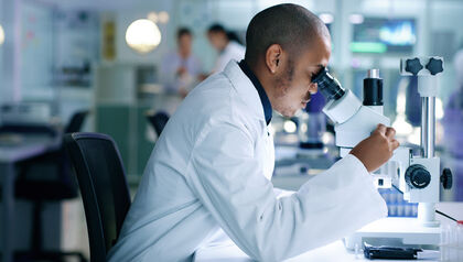 Scientist looking at sample through a microscope