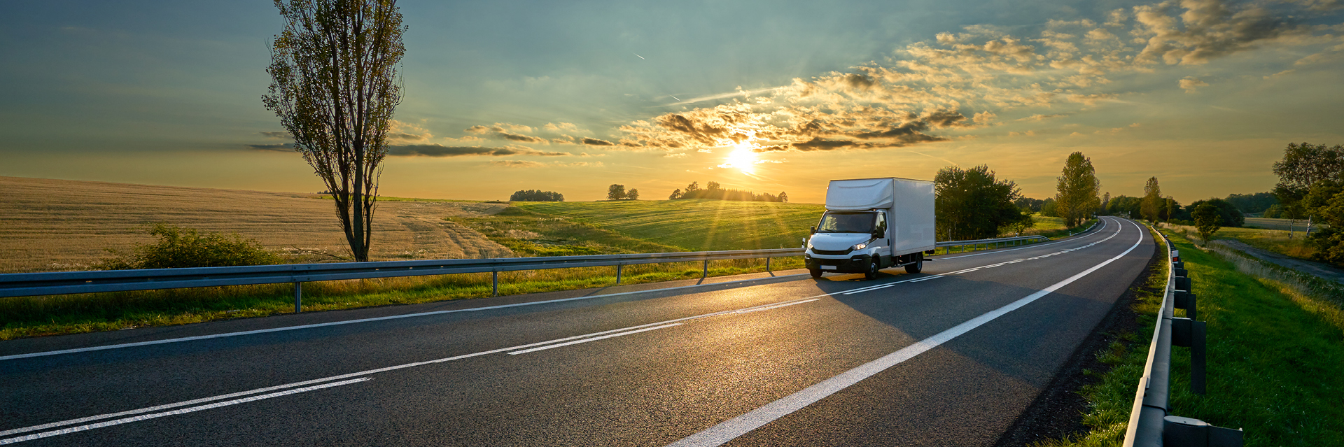 A moving truck driving on a highway at sunset
