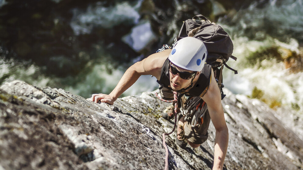Mann mit HOYA-Sonnenbrille mit speziellen Sportgläsern beim Bergsteigen