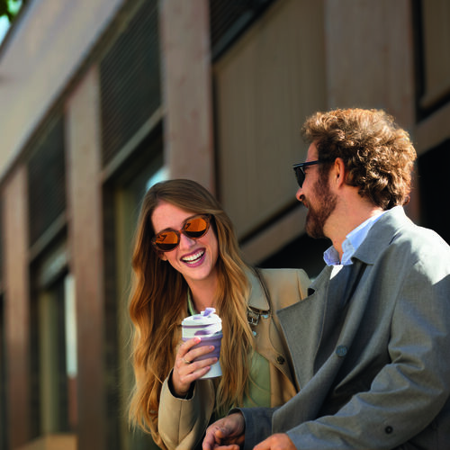 Two people drinking coffee outside while wearing sunglasses