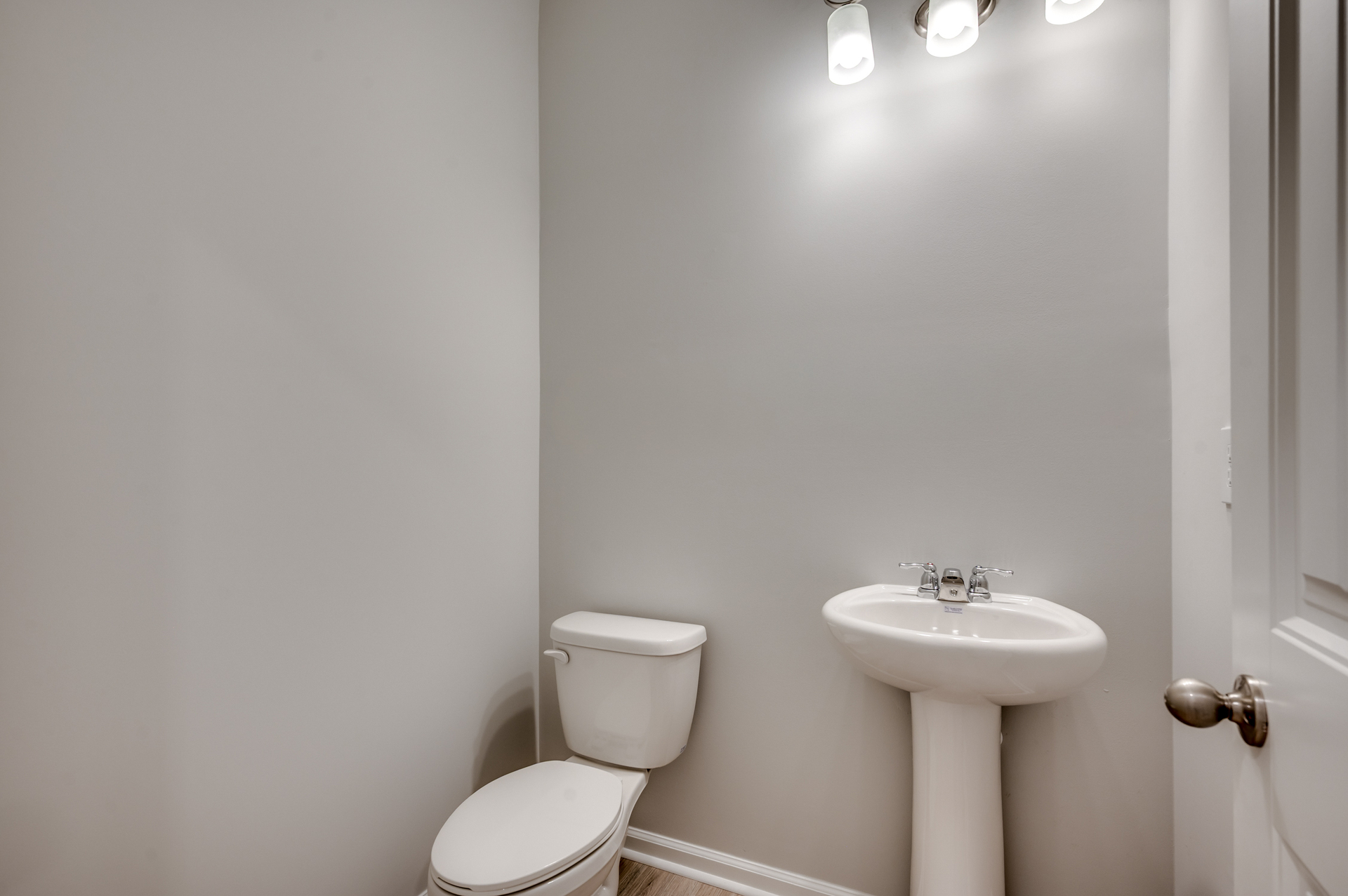 convenient bathroom with sink, pendant lighting and tan walls 