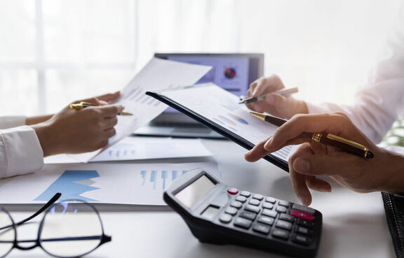 Business people sitting at a desk looking at documents and tablet devices 