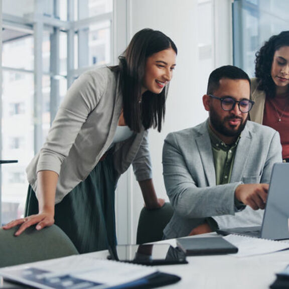 Two women and a man collaborating over a laptop