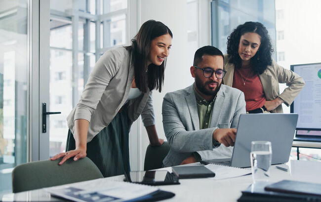 Two women and a man collaborating over a laptop