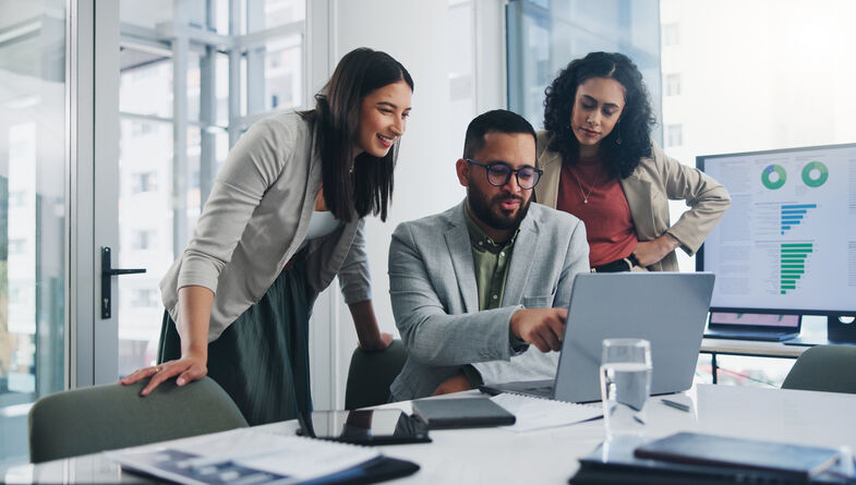 Two women and a man collaborating over a laptop
