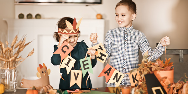 Two children unwrap a garland that says 