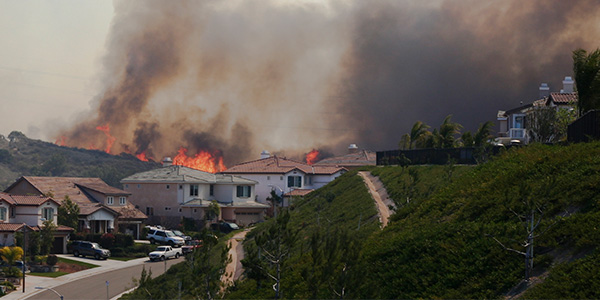 A wildfire burns on a hillside over a neighborhood