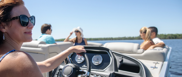 Smiling woman in sunglasses at the wheel of a cruising motor boat