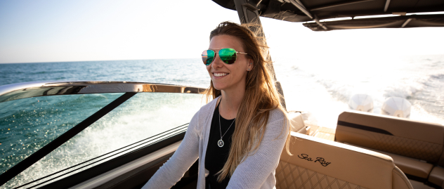 Smiling woman in mirrored sunglasses driving powerboat fitted with Lenco trim tabs