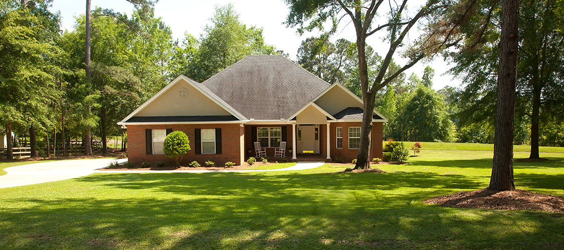 A nice brick home on a well manicured lawn surrounded by trees