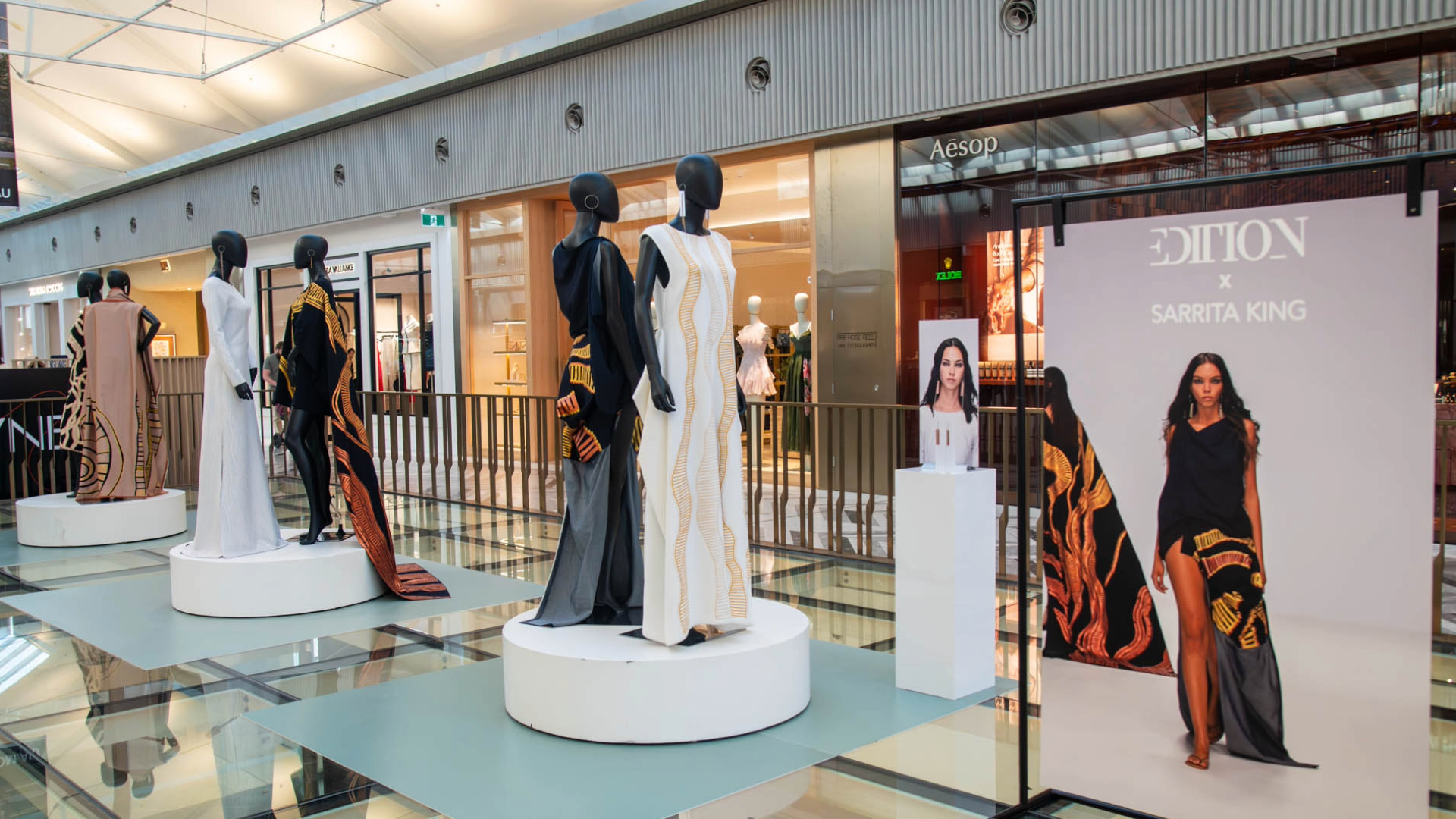Fashion display featuring garments from the EDITION x Sarrita King collaboration at Canberra Centre, with mannequins dressed in contemporary designs inspired by First Nations storytelling and artistic motifs, alongside a campaign display highlighting the collection and jewellery by Phoebe Porter.