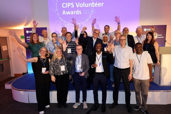 Large group of volunteers with arms in the arm, sign behind them says 'CIPS Volunteer awards'