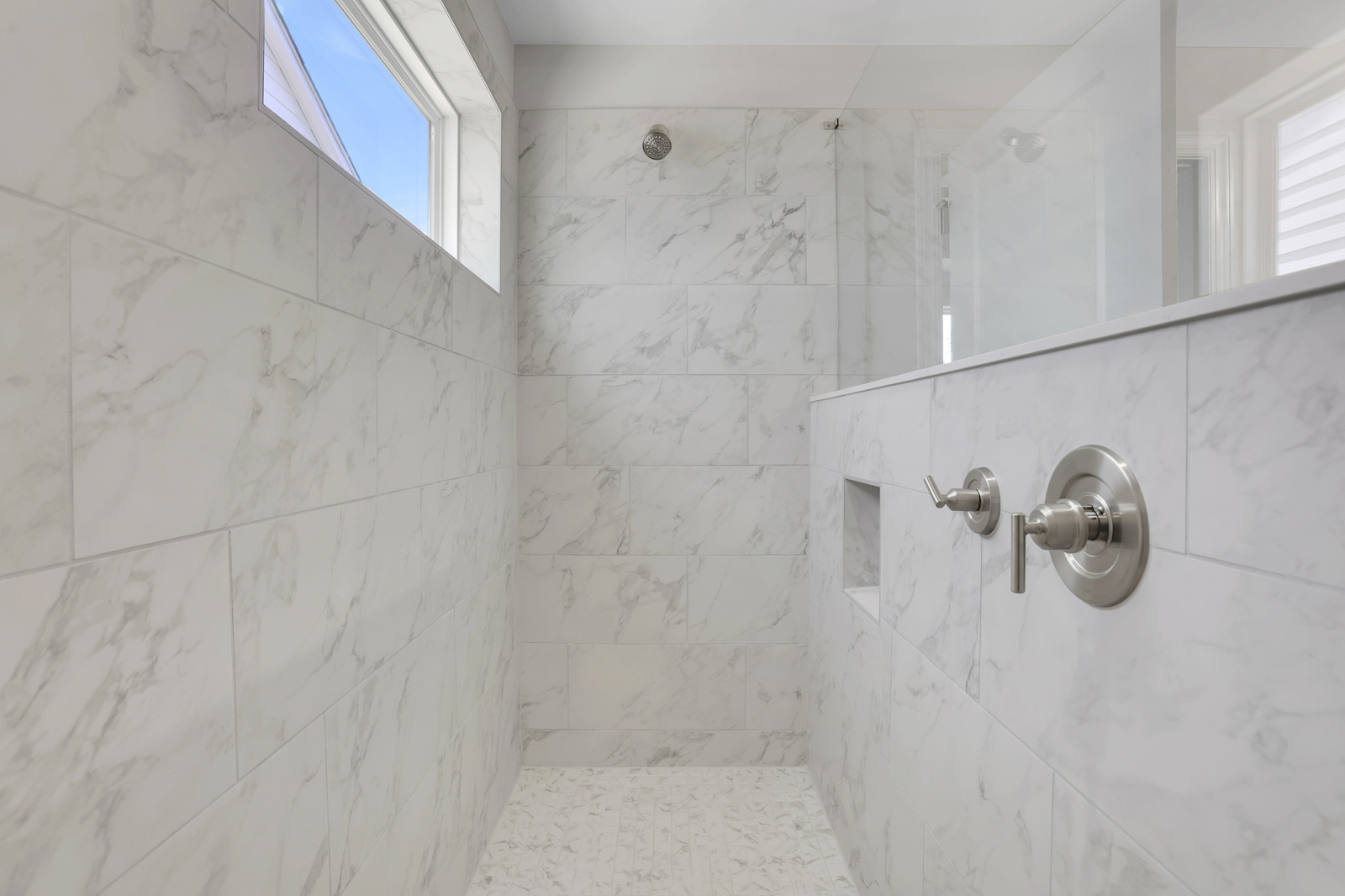 primary bathroom with walk-in shower with light tile