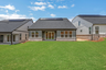 back of 1-story home with covered patio and lush grass