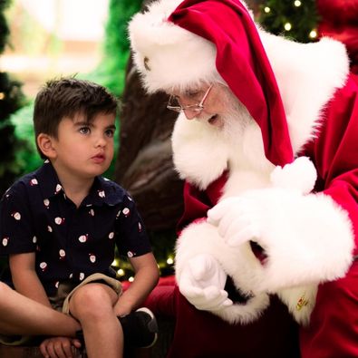 Santa leans in and gestures with his hands as a child sits beside him in a quiet Sensitive Santa session 