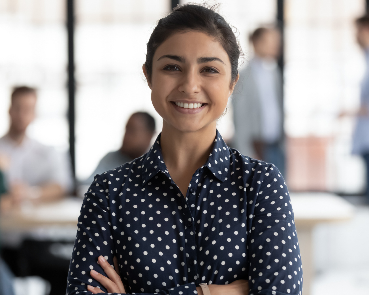 woman in polka dot top smiling with arms crossed