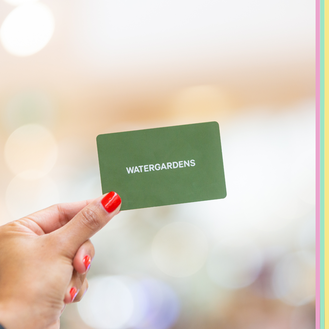 Woman's hand holding a Watergardens gift card.