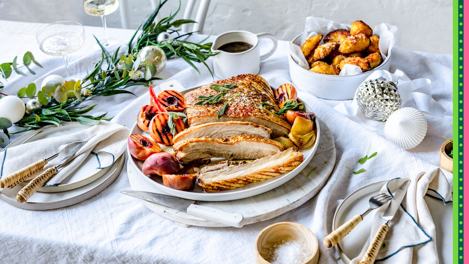 Australian Christmas Lunch or Dinner featuring Crispy Pork Belly served on a white plate and beech wood chopping board with char grilled stone fruit, roast potatoes and gravy.