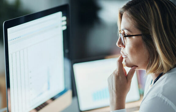 Woman at a desk looking at a brightly lit computer monitor