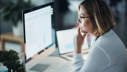 Woman at a desk looking at a brightly lit computer monitor