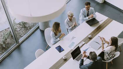 Top down view of a group of business people sitting at a long conference table