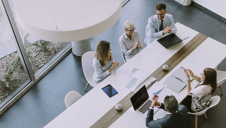 Top down view of a group of business people sitting at a long conference table