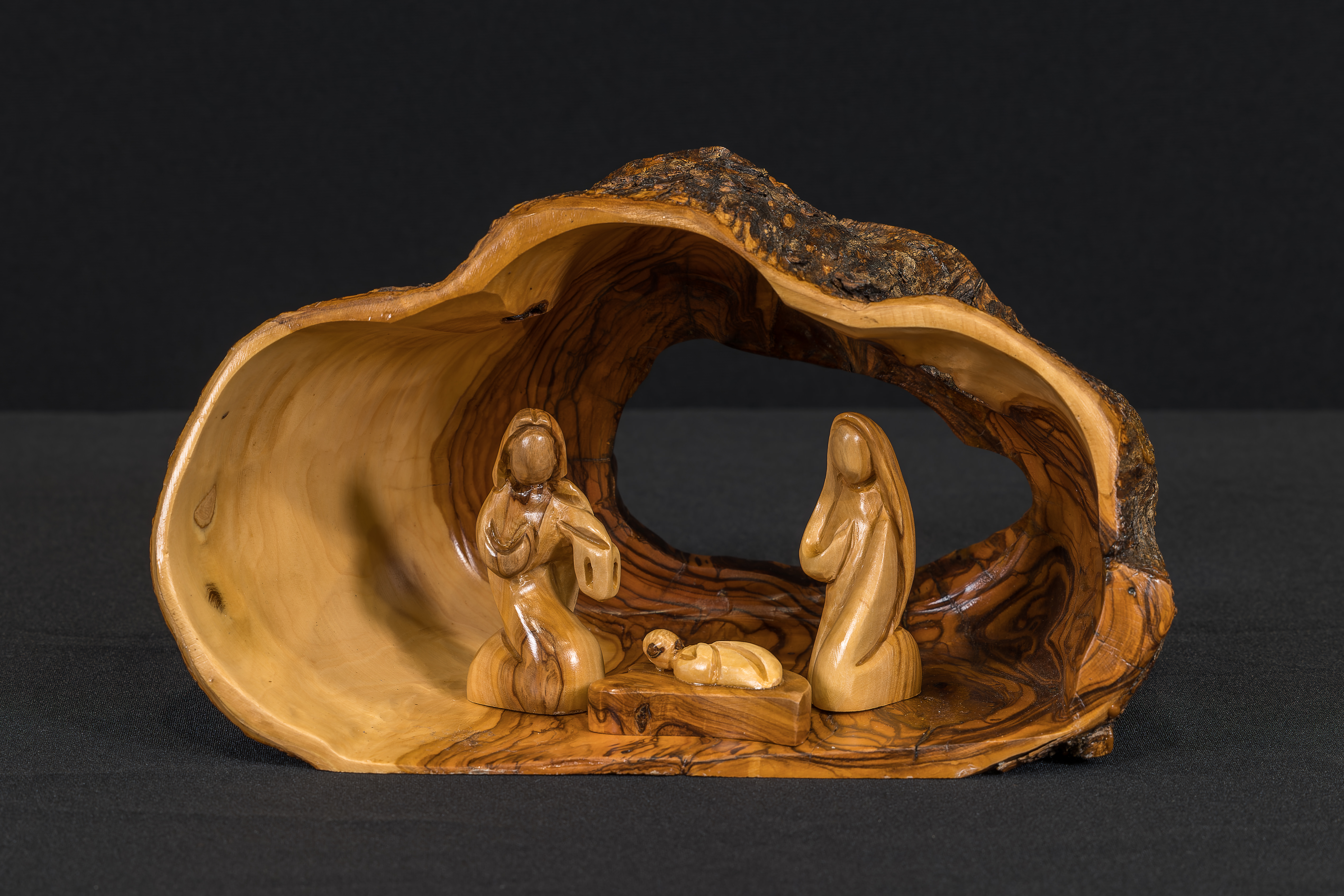 A hollowed-out portion of an olive tree trunk serves as the stable for this crèche and contains the Holy Family.