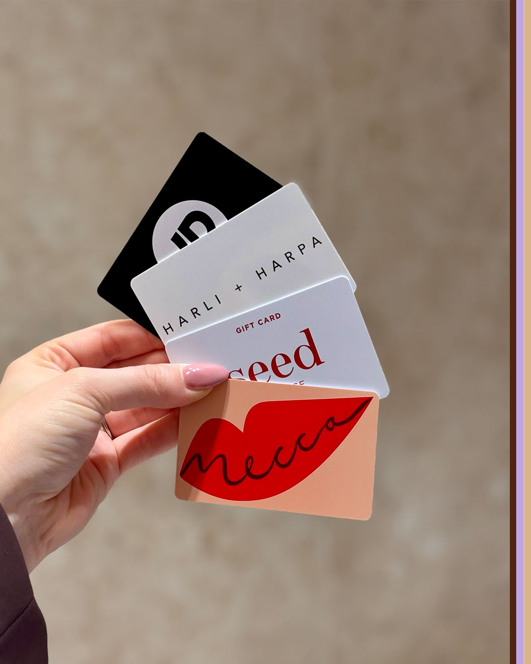A woman hand holding Mecca, Seed Heritage, Harli + Harpa, and JD Sports Gift Cards