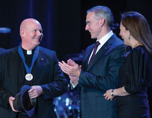 Father Matthew Keller is congratulated by Supreme Knight Kelly and his wife, Vanessa
