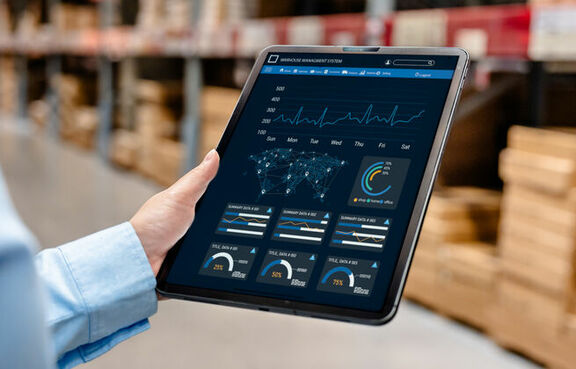Man in a warehouse looking at ERP dashboard on a tablet 