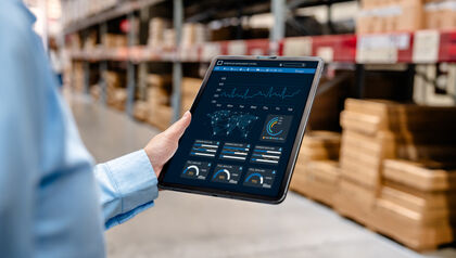 Man in a warehouse looking at ERP dashboard on a tablet 