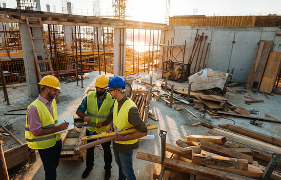 Group of architects and engineers wearing hard hats at a job site 