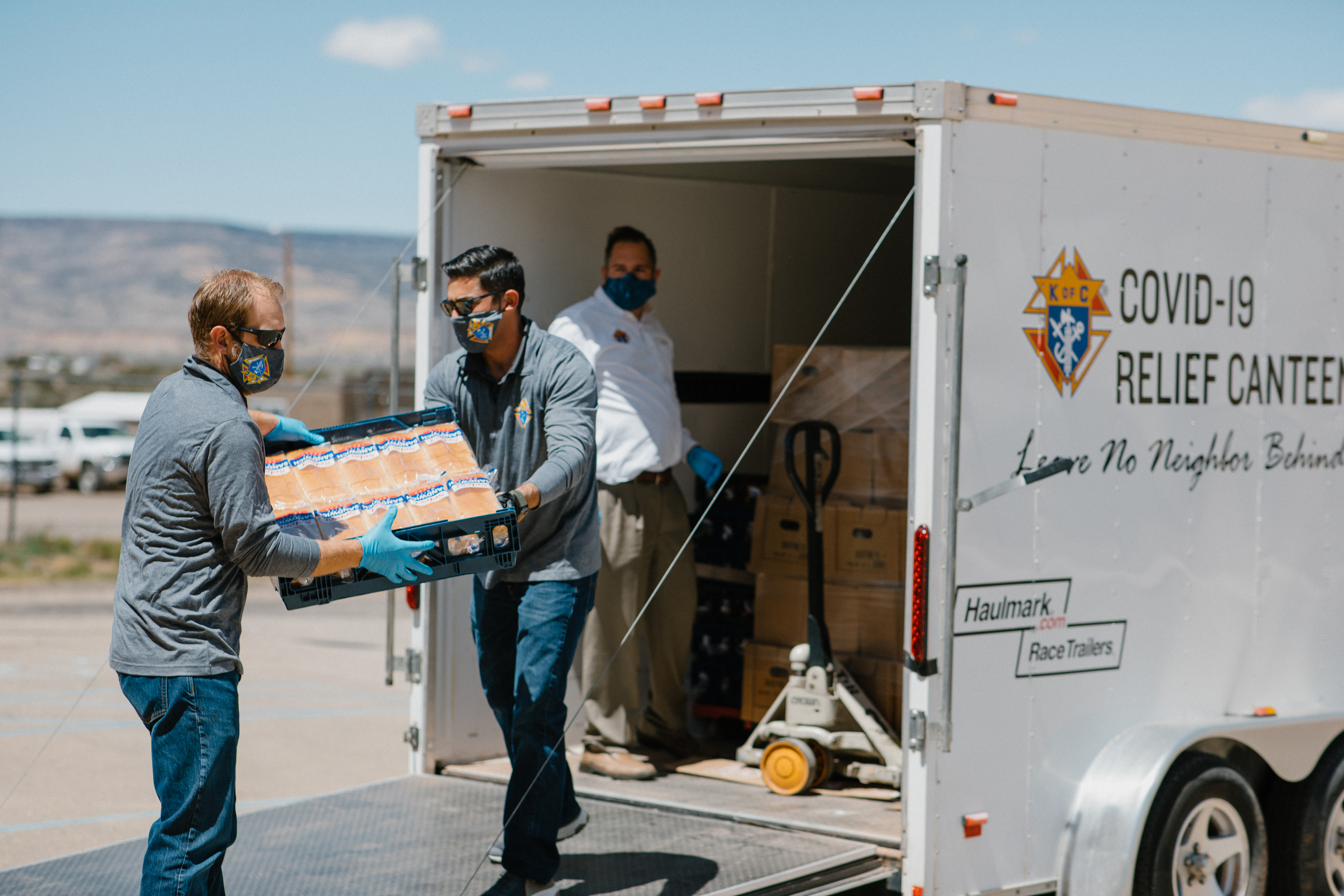 Knights wear masks and gloves while unloading a trailer of supplies for the Acoma people in New Mexico to help those in need during the COVID pandemic.